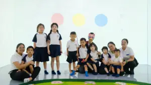 Educators and young learners posing together in the sensory projection room during a special literacy and storytelling event at Sproutville International School.