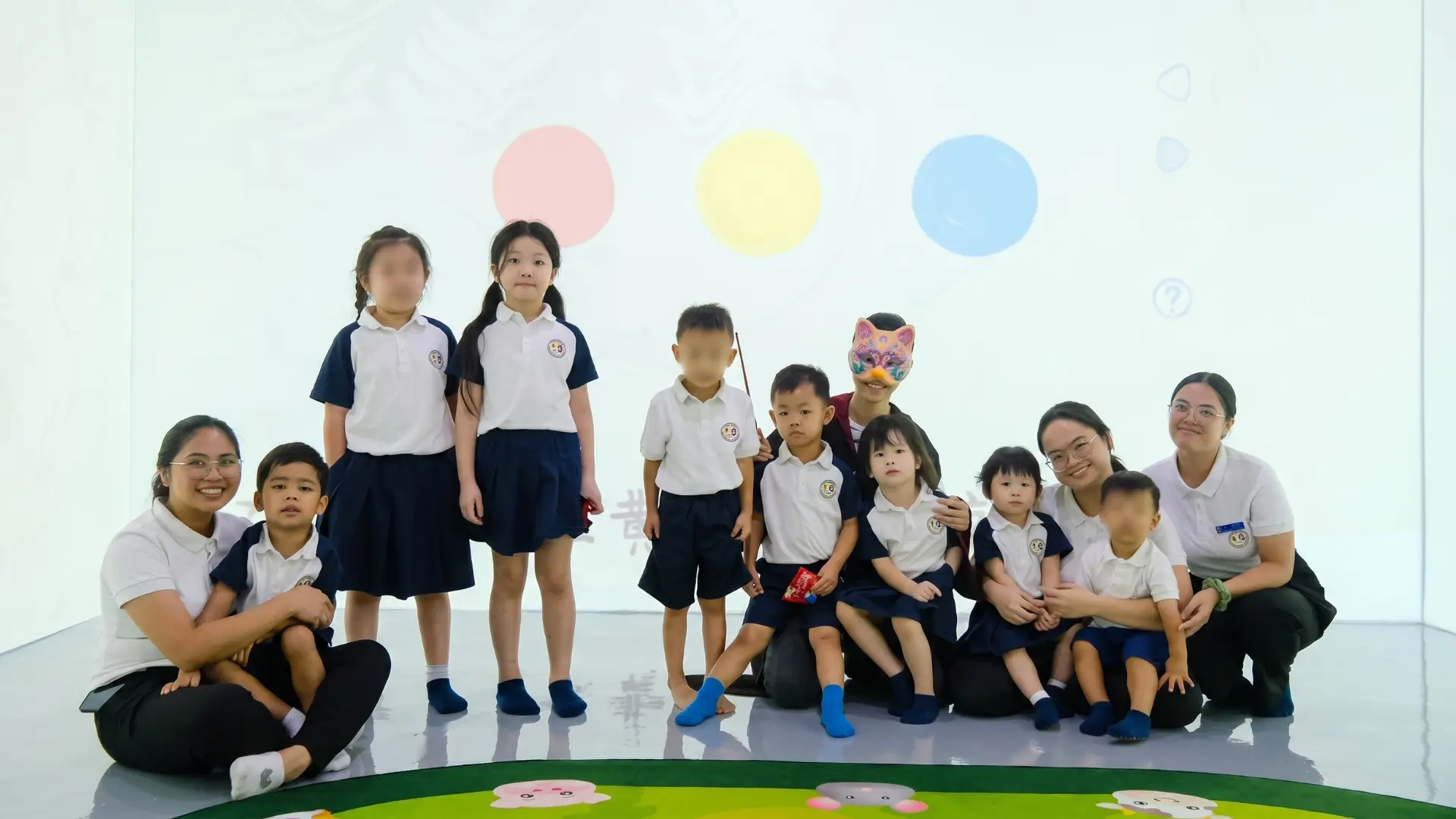 Educators and young learners posing together in the sensory projection room during a special literacy and storytelling event at Sproutville International School.