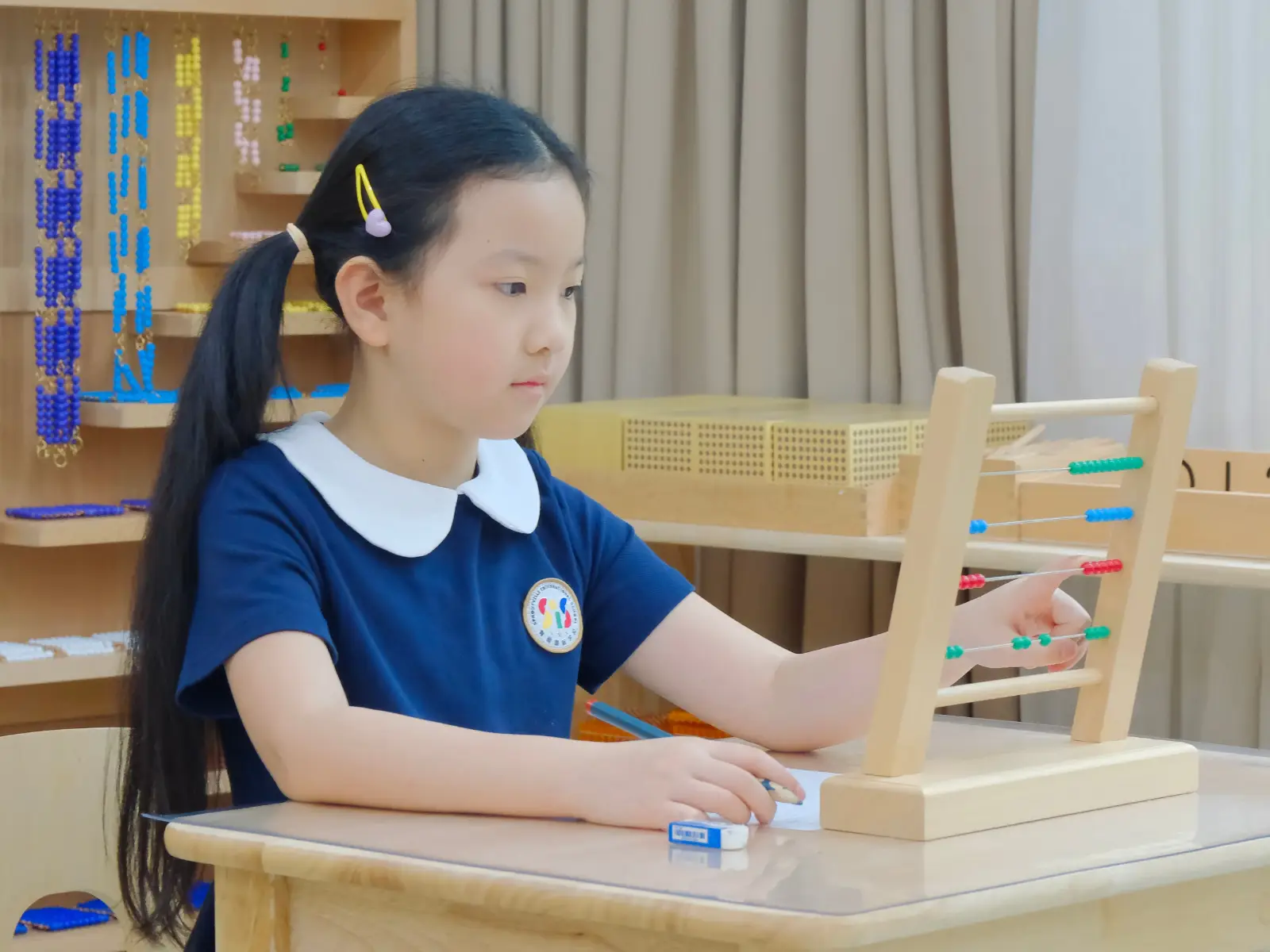 Focused student at Sproutville International School learning Montessori math concepts using a wooden bead frame abacus.
