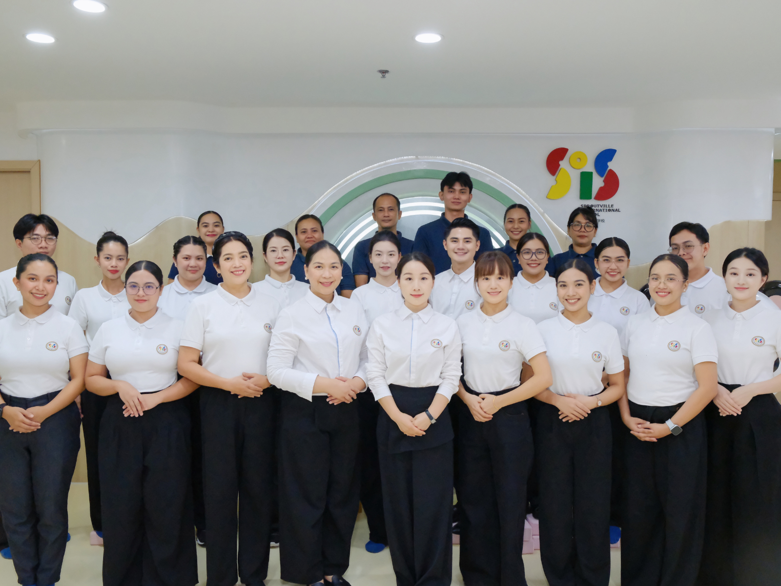 Group photo of the dedicated teaching and non-teaching staff at Sproutville International School gathered in the modern entrance lobby.